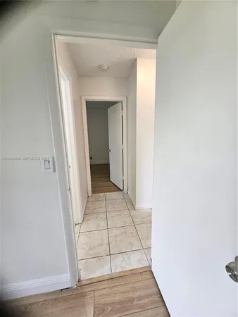 a view of an empty room with wooden floor and window