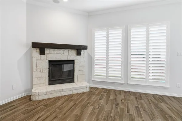 an empty room with wooden floor fireplace and windows