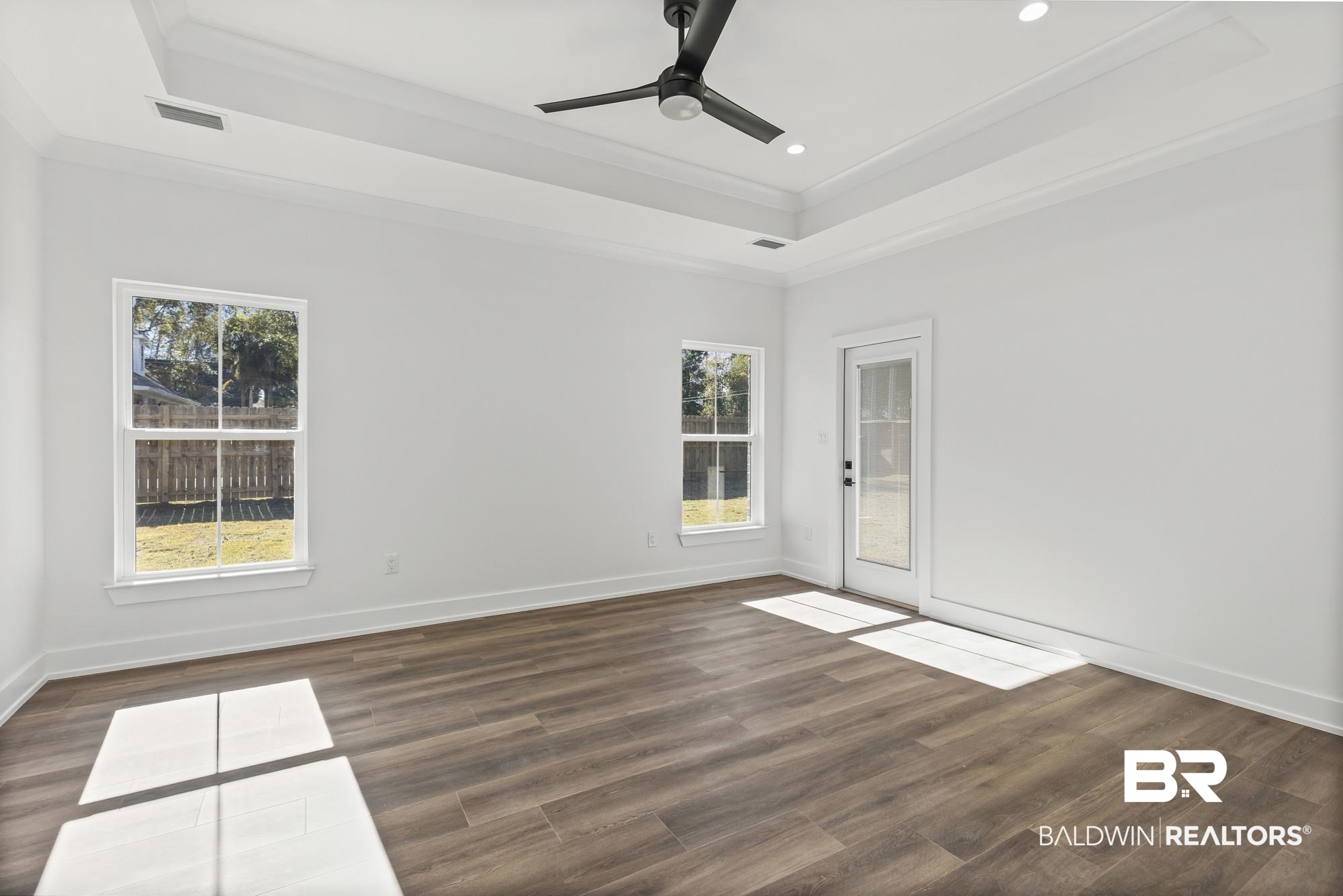 10180 Pineview Drive Foley, AL 36535 - Photo 19 of 47 Empty room featuring a tray ceiling, ornamental molding, dark wood-type flooring, a ceiling fan, and recessed lighting