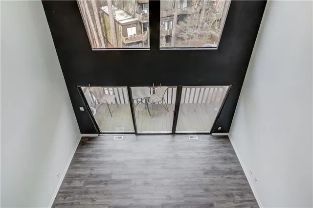 an empty room with wooden floor fan and windows