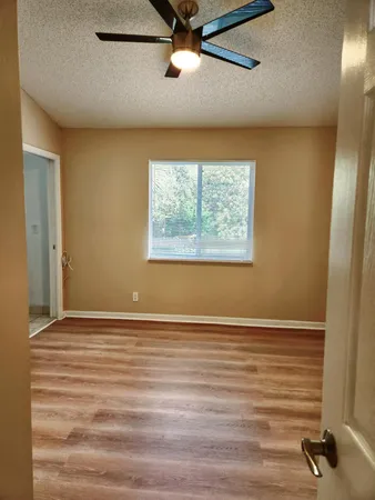 a view of an empty room with a window and a ceiling fan