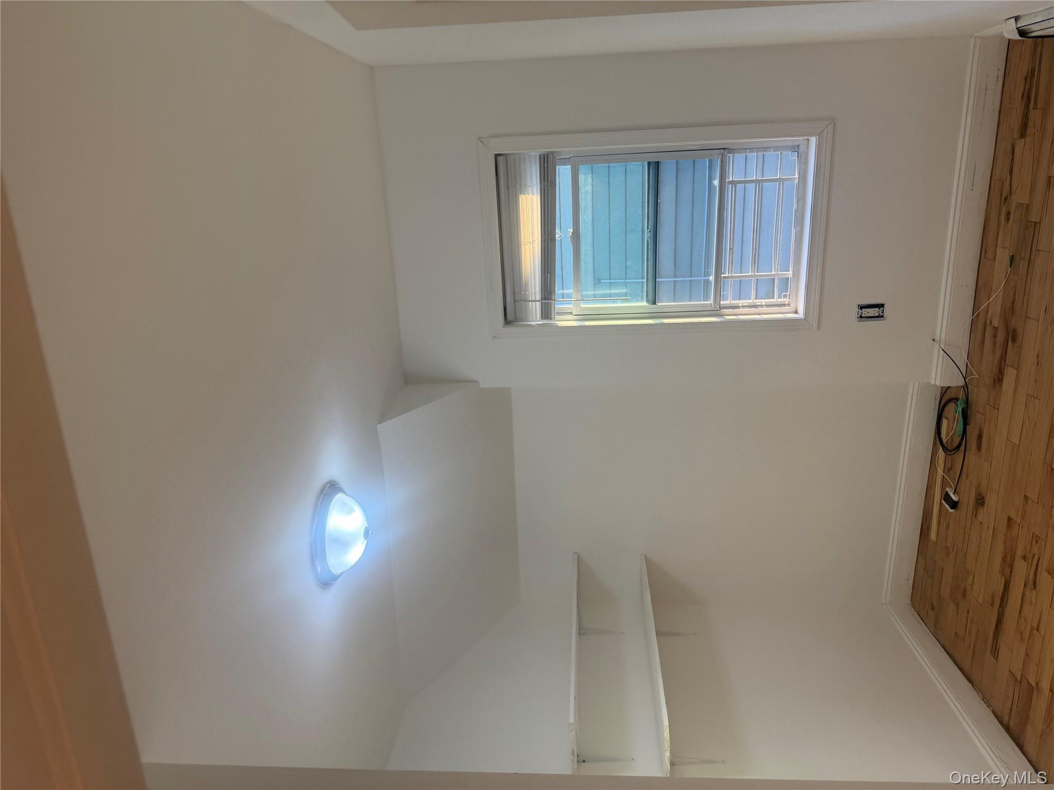 28 Clinton Avenue, Unit 2 Hempstead, NY 11096 - Photo 2 of 5 a view of an empty room with wooden floor and a window