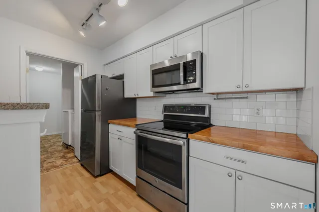 a kitchen with stainless steel appliances white cabinets a stove a microwave and a refrigerator