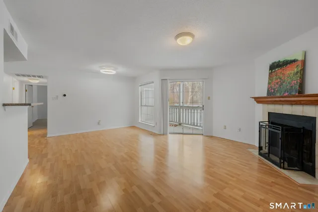 a view of empty room with wooden floor and fireplace