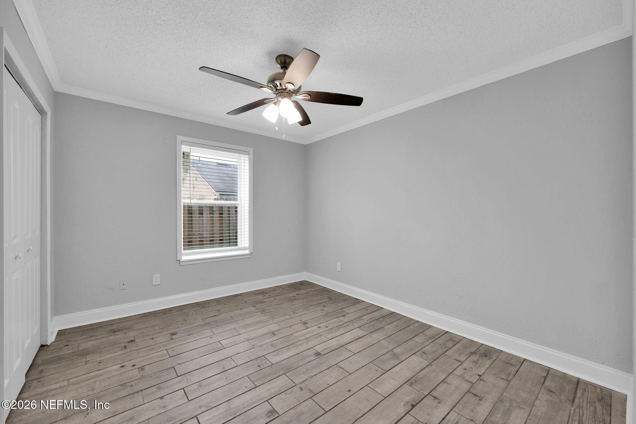 2494 Spring Vale Road Jacksonville, FL 32246 - Photo 23 of 36 an empty room with wooden floor fan and windows