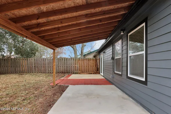 a view of backyard with large trees and wooden fence