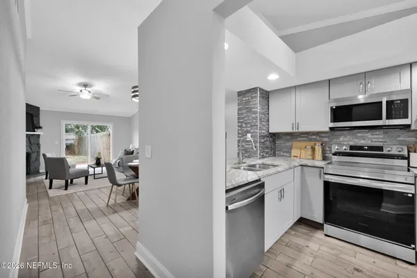 a kitchen with stainless steel appliances granite countertop a stove top oven a sink dishwasher and a fireplace with wooden floor