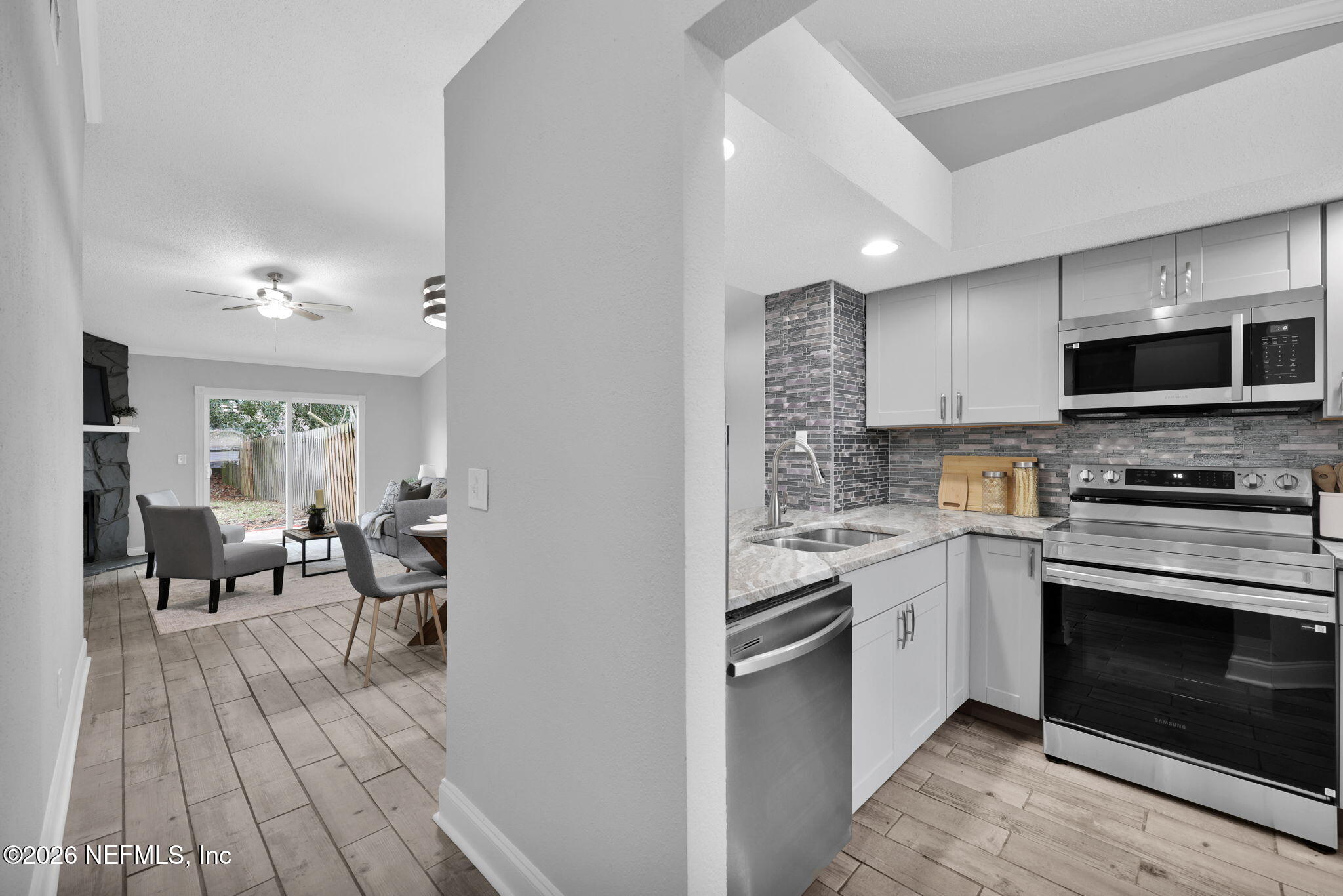 2494 Spring Vale Road Jacksonville, FL 32246 - Photo 5 of 36 a kitchen with stainless steel appliances granite countertop a stove top oven a sink dishwasher and a fireplace with wooden floor