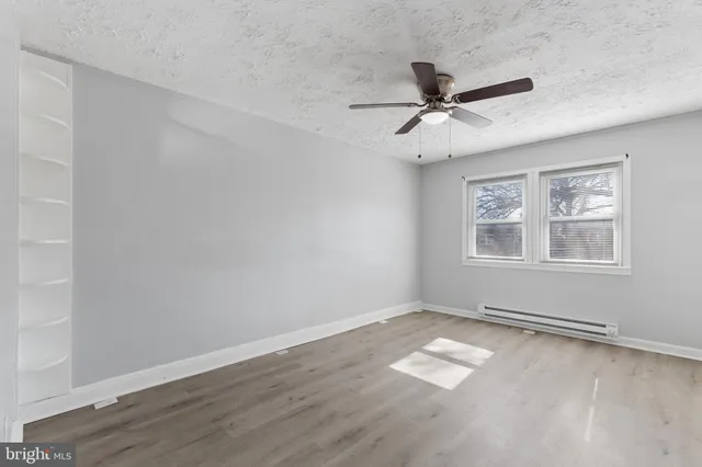 a view of a livingroom with a ceiling fan a kitchen space with wooden floor