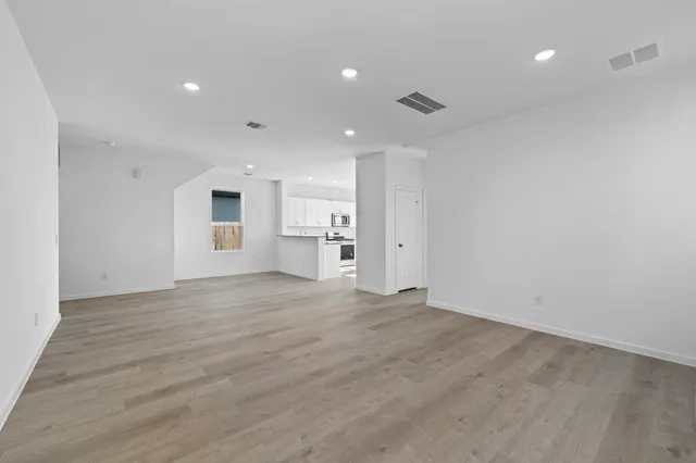 a view of empty room with kitchen and window