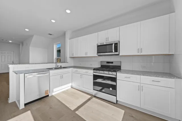 a kitchen with granite countertop white cabinets and stainless steel appliances