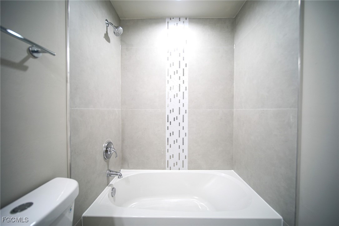 1018 Genoa Avenue South Lehigh Acres, FL 33974 - Photo 10 of 22 a bathroom with a white bath tub and a shower curtain