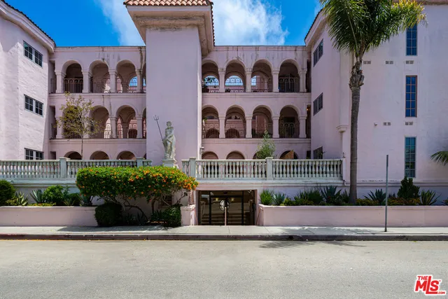 a front view of a multi story residential apartment building with yard and potted plants