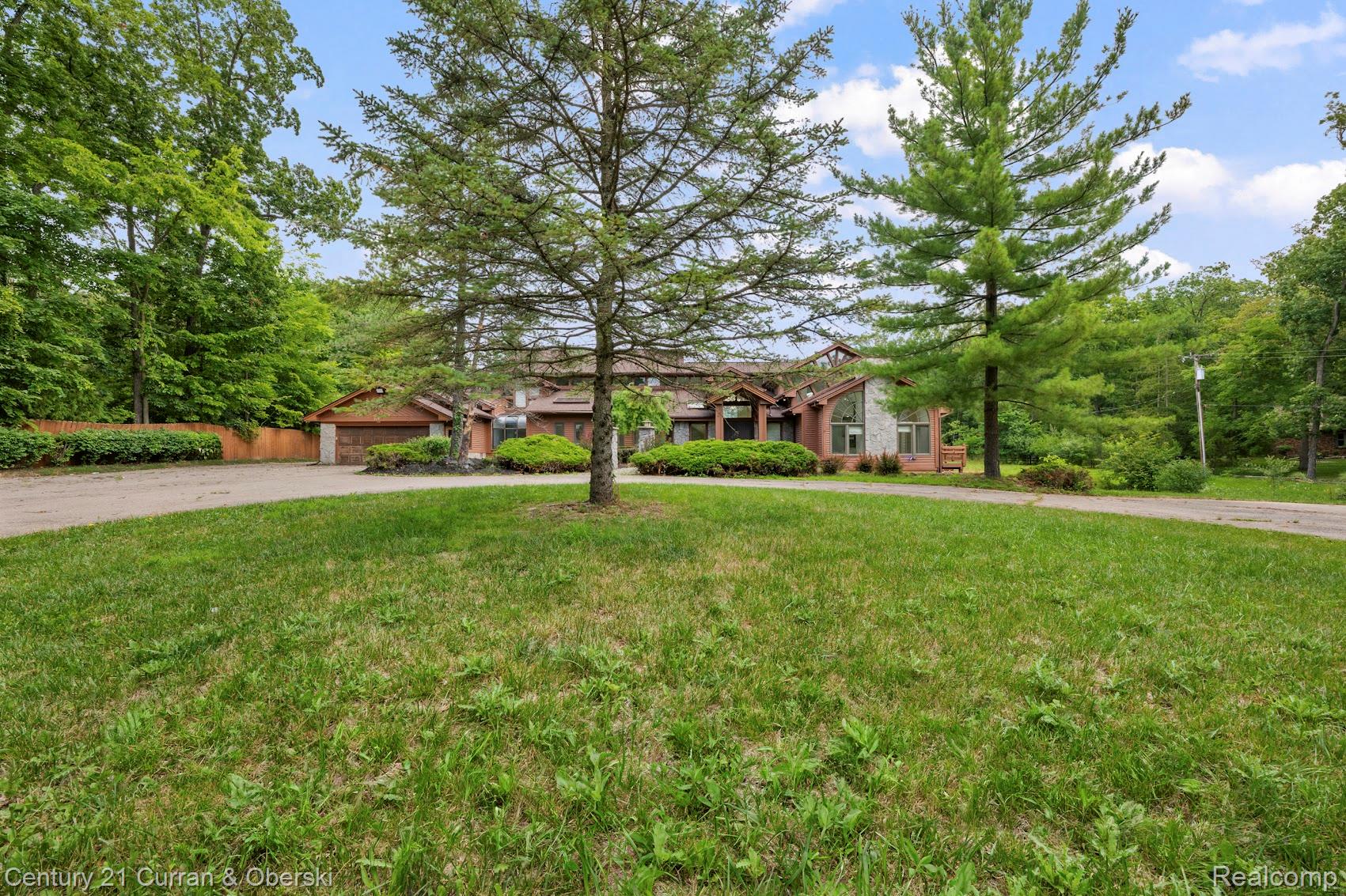 8785 Warren Road Plymouth, MI 48170 - Photo 35 of 46 Spacious front yard with mature trees and a paved driveway leading to a multi-level residence