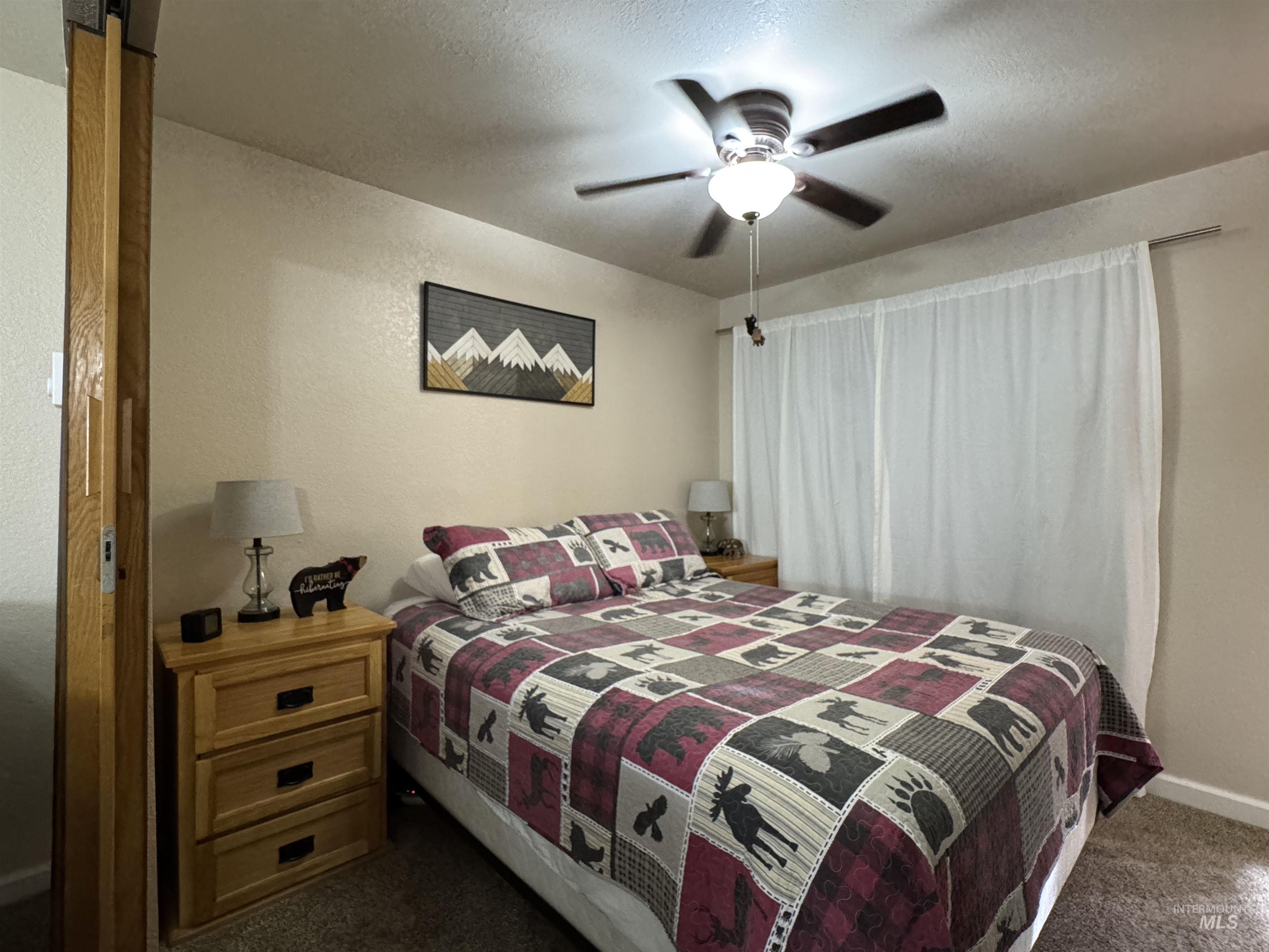 304 McBride Street, Unit 107 107 McCall, ID 83638 - Photo 14 of 28 Bedroom with a ceiling fan, dark carpet, a textured ceiling, and a textured wall