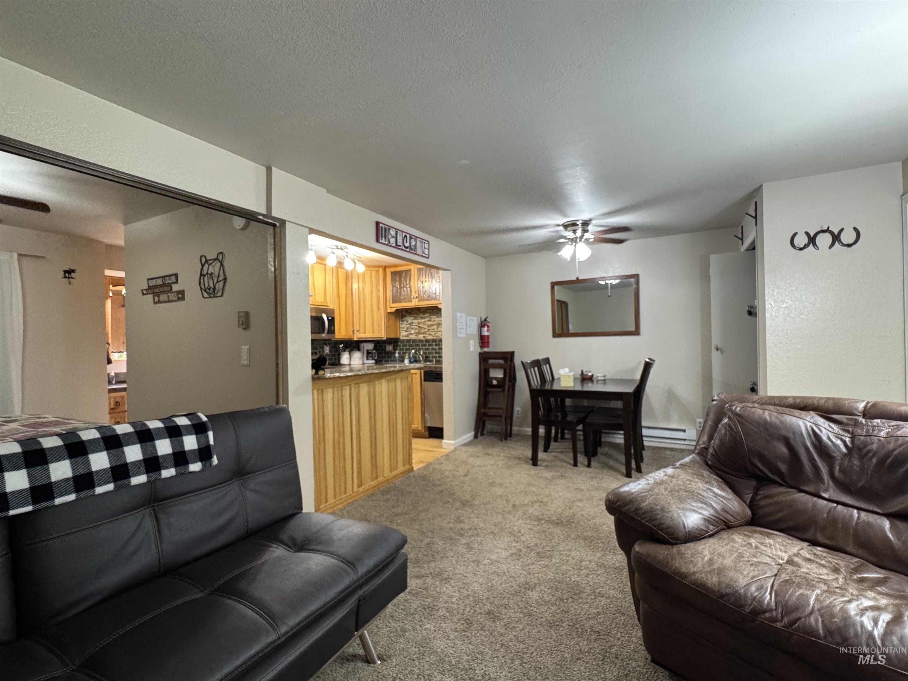 304 McBride Street, Unit 107 107 McCall, ID 83638 - Photo 15 of 28 Living area featuring a ceiling fan, light carpet, a baseboard radiator, and a textured ceiling