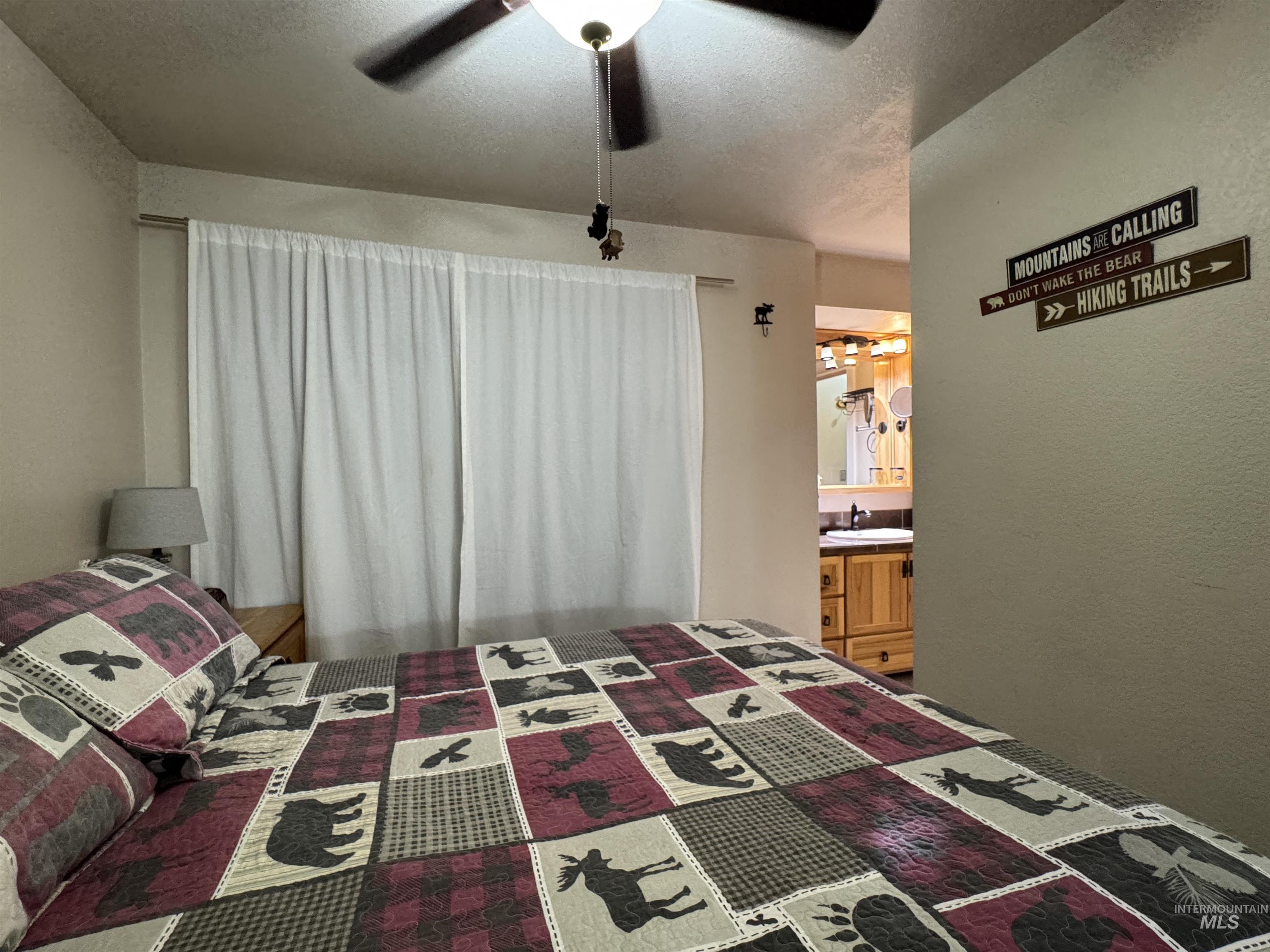 304 McBride Street, Unit 107 107 McCall, ID 83638 - Photo 17 of 28 Bedroom with a textured ceiling, ceiling fan, a textured wall, and ensuite bathroom