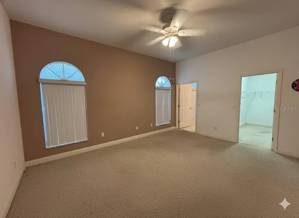 an empty room with windows and fan