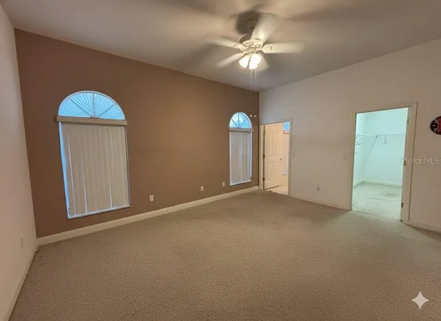 an empty room with windows and fan