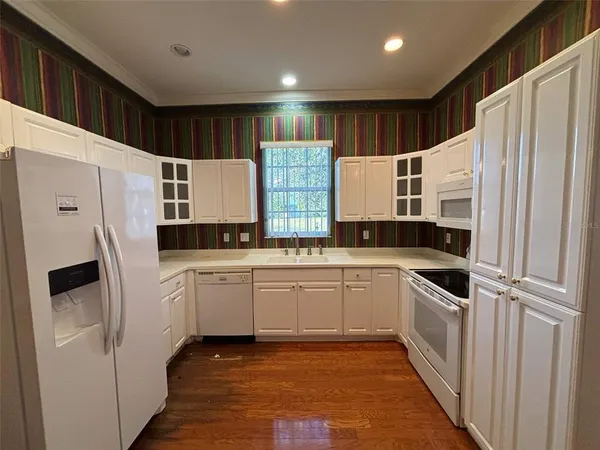 a kitchen with granite countertop a refrigerator and white cabinets