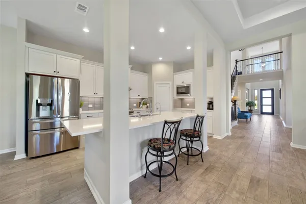 a kitchen with stainless steel appliances kitchen island granite countertop a refrigerator and a stove top oven with white countertops