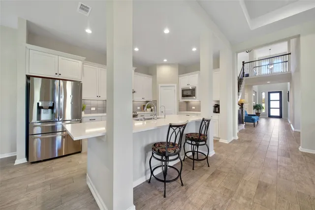 a kitchen with stainless steel appliances kitchen island granite countertop a refrigerator and a stove top oven with white countertops