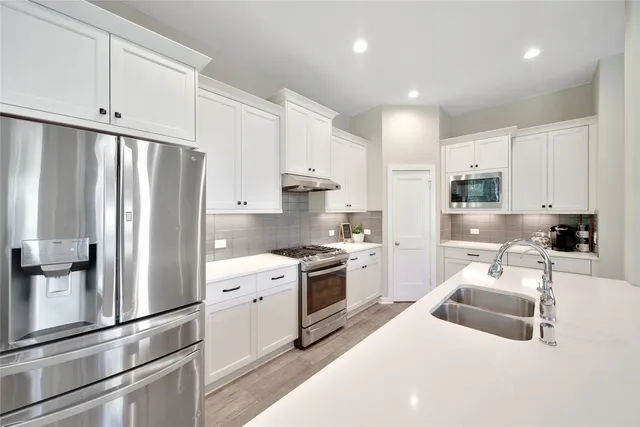 a kitchen with stainless steel appliances white cabinets and wooden floors