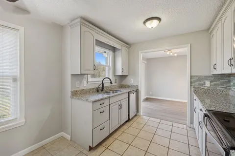 a view of an empty room with window and chandelier fan