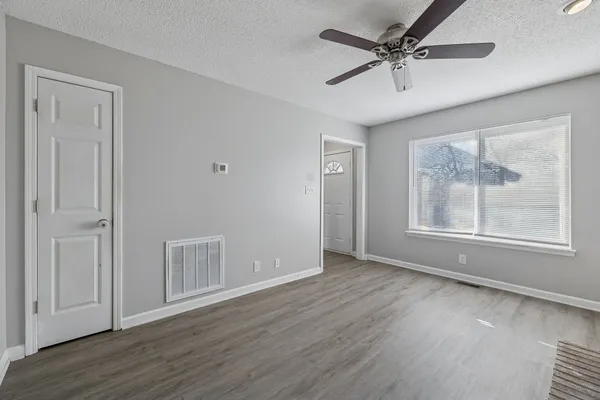 a view of an empty room with a window and wooden floor