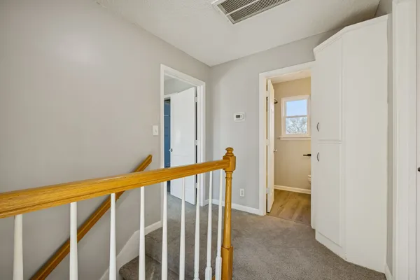 a view of a hallway with wooden floor and a bathroom
