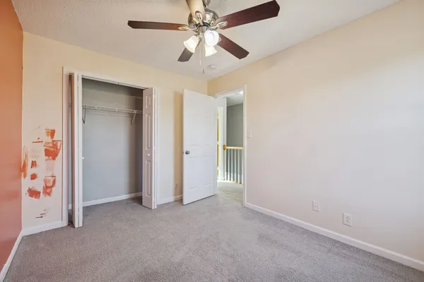 an empty room with closet and a ceiling fan