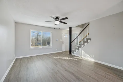 a view of empty room with wooden floor and fan