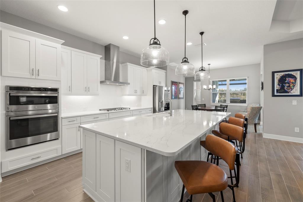 14375 Skipping Stone Loop Parrish, FL 34219 - Photo 15 of 87 a large kitchen with stainless steel appliances kitchen island granite countertop a table chairs and a refrigerator