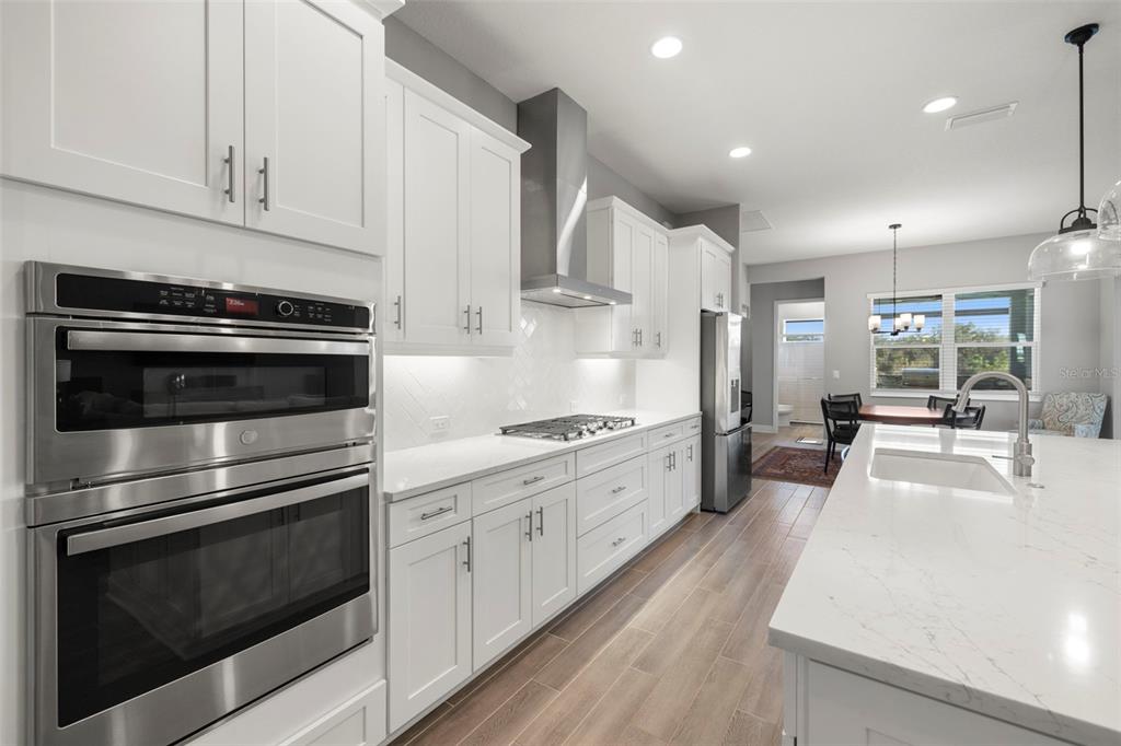 14375 Skipping Stone Loop Parrish, FL 34219 - Photo 16 of 87 a kitchen with stainless steel appliances kitchen island granite countertop a stove a sink and white cabinets