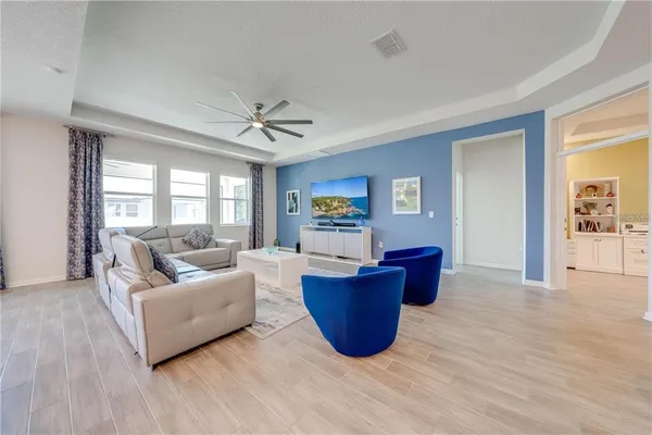 a living room with furniture kitchen view and a wooden floor