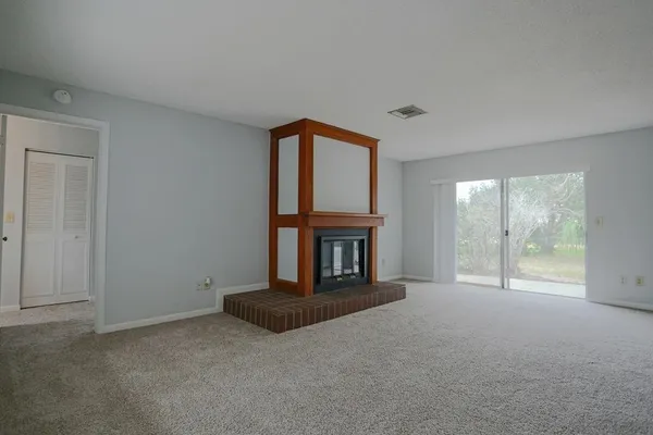 a view of an empty room with a fireplace and a window
