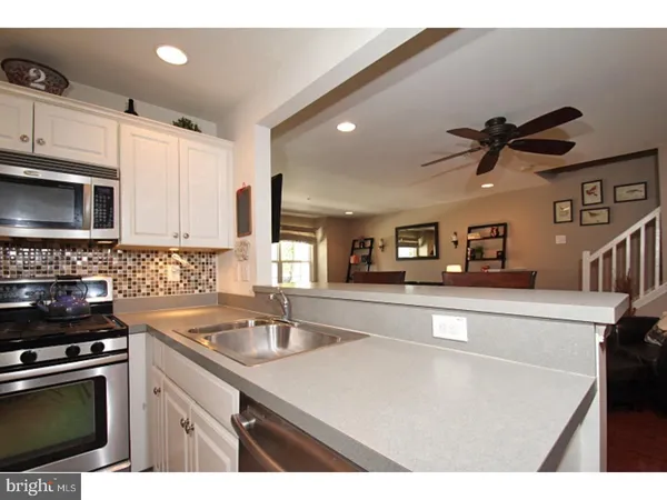 a kitchen with granite countertop a sink stainless steel appliances and white cabinets