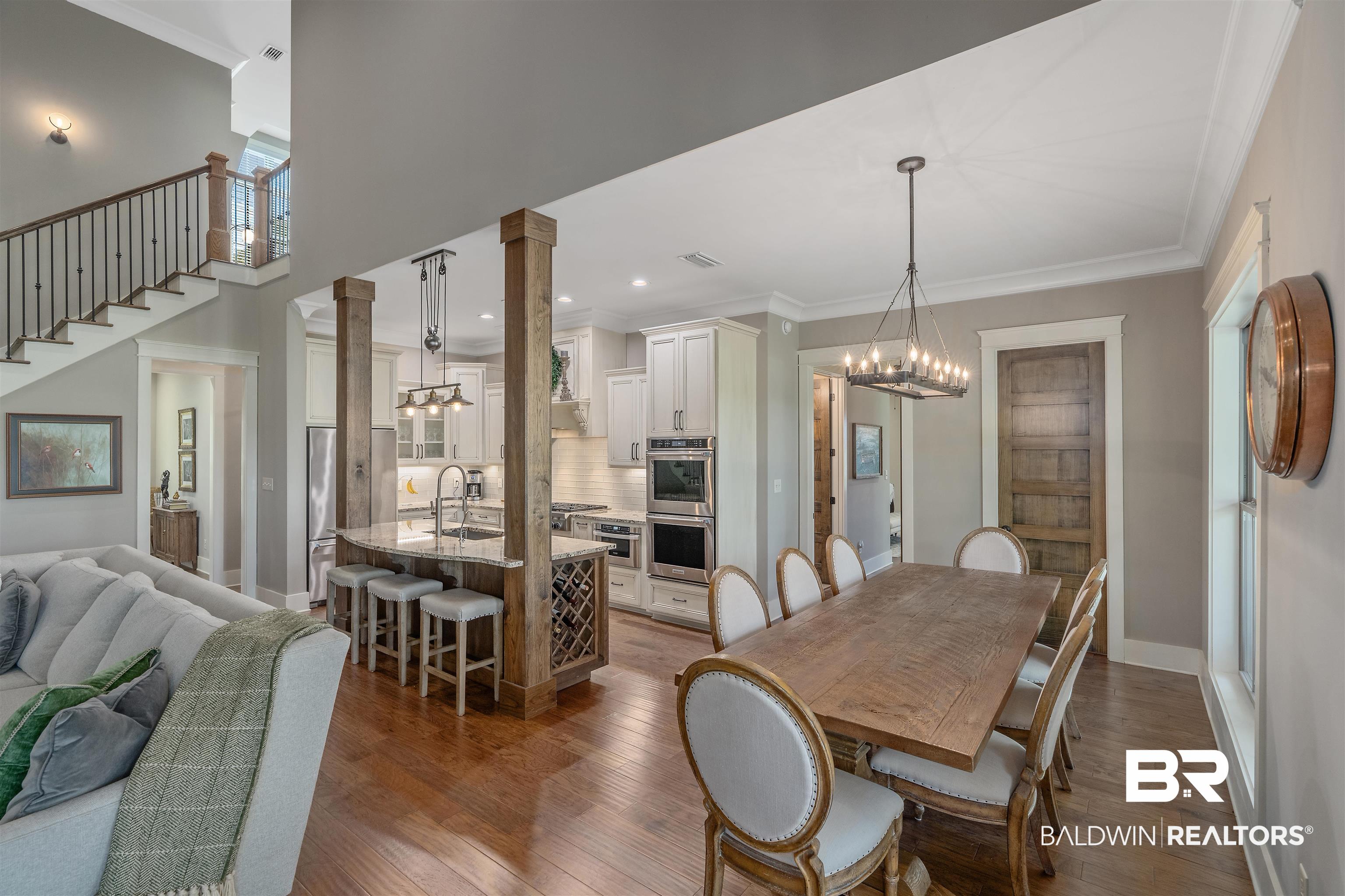 8753 Bishop Road Fairhope, AL 36532 - Photo 22 of 59 Open-concept living space featuring hardwood flooring, a kitchen island with seating, built-in double ovens, and a formal dining area with a linear chandelier
