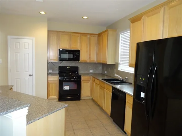 a kitchen with granite countertop stainless steel appliances a stove a refrigerator a sink and a microwave
