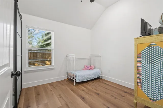 a view of a refrigerator in kitchen and an empty room with wooden floor
