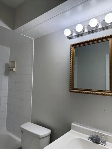 a bathroom with a granite countertop sink and a toilet
