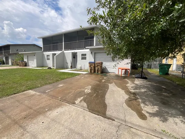 a view of a house with a yard and large tree