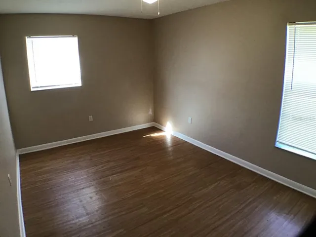 an empty room with wooden floor and windows