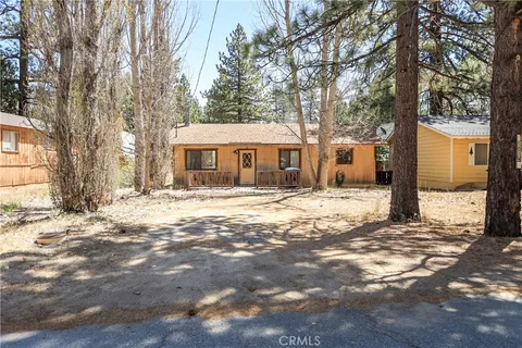 a front view of a house with a yard covered with snow and trees