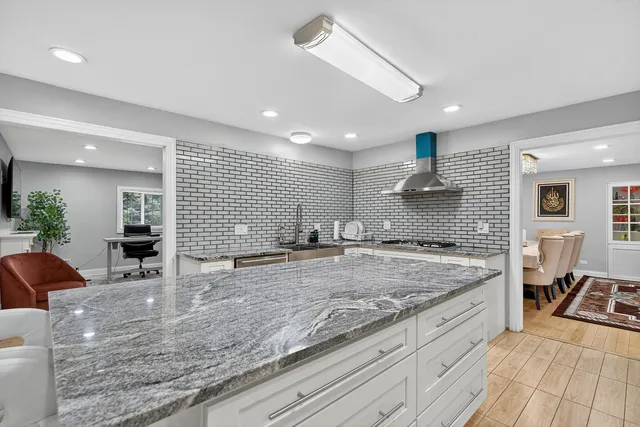 a large kitchen with granite countertop a large counter top stainless steel appliances and cabinets