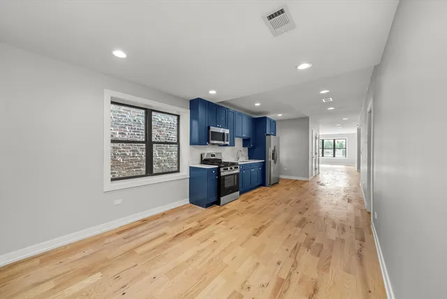 a open kitchen with kitchen island a stove a sink dishwasher and a refrigerator with wooden floor