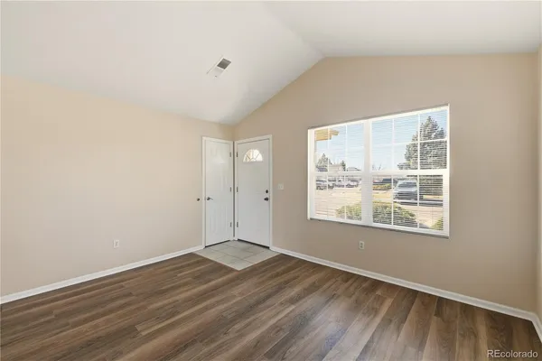 an empty room with wooden floor and windows