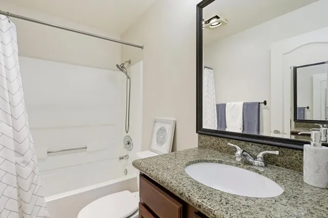 a bathroom with a granite countertop sink toilet mirror and shower