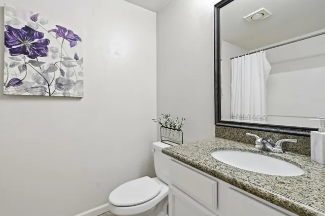 a bathroom with a granite countertop sink a toilet and a mirror