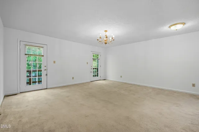 a view of an empty room with a chandelier fan